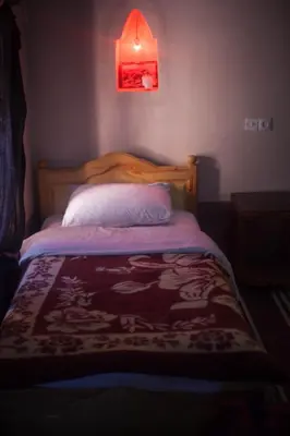 a bed in a bedroom with a red light above it at Kasbah Ait Kassi in Boumalne
