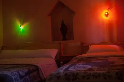 a dark room with two beds and lights on the wall at Kasbah Ait Kassi in Boumalne