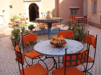 a table and chairs with a bowl of fruit on it at Kasbah Ait Kassi in Boumalne