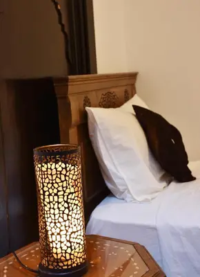 a lamp sitting on a table next to a bed at Dar Aya Fes in Fès