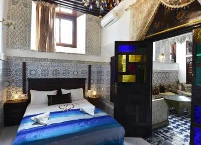 a bedroom with a king sized bed and a living room at Dar Aya Fes in Fès