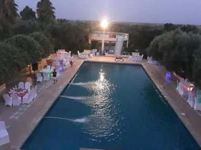 a swimming pool with white chairs and a building at Hotel Complex Europe in Guercif