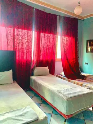 two beds in a room with red curtains at Hotel Complex Europe in Guercif