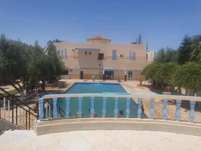 a large house with a swimming pool in front of it at Hotel Complex Europe in Guercif