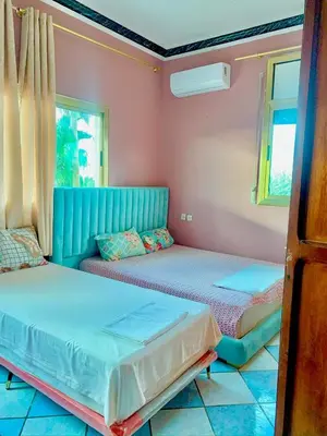 two beds in a room with pink walls and windows at Hotel Complex Europe in Guercif