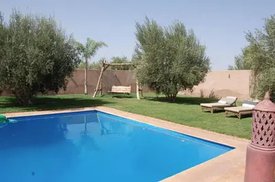 a blue swimming pool in a yard with trees at Villa Baraka in Marrakech