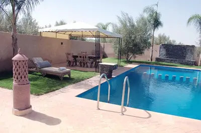 a swimming pool with a table and an umbrella at Villa Baraka in Marrakech