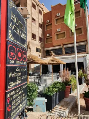 a sign in front of a building with a restaurant at Hotel Achark in Bou Arfa