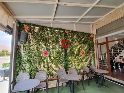 a wall covered in flowers with tables and chairs at Hotel Achark in Bou Arfa