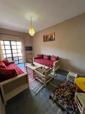 a living room with a red couch and a table at Tazart Lodge in Marrakech