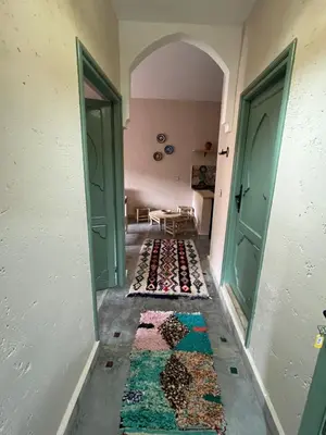 a hallway with two green doors and a rug on the floor at Tazart Lodge in Marrakech