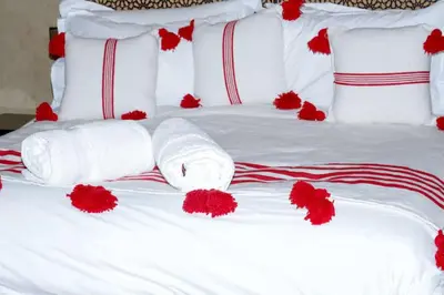 a white bed with red flowers on it at Desert Magic Camp in Merzouga