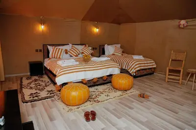 two beds in a room with pumpkins on the floor at Desert Magic Camp in Merzouga
