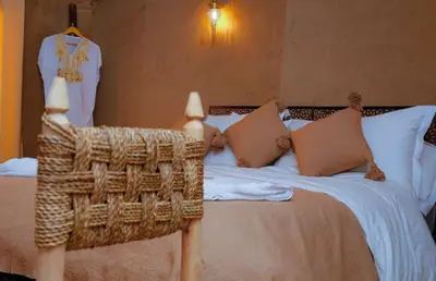 a bedroom with a bed with a wicker chair at Desert Magic Camp in Merzouga