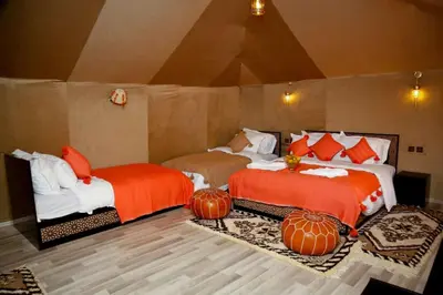 two beds in a room with pumpkins on the floor at Desert Magic Camp in Merzouga