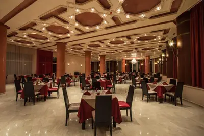 a dining room with tables and chairs in a building at Hotel Tafilalet in Meknès