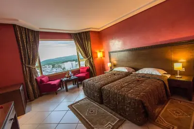 a hotel room with a bed and a large window at Hotel Tafilalet in Meknès