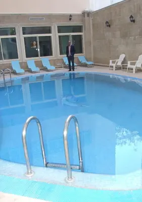 a man standing in front of a large swimming pool at Hotel Tafilalet in Meknès