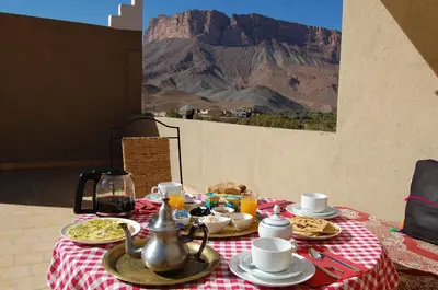 a table with plates of food and a mountain in the background at Auberge Amellagou in Amellagou