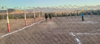 three people are playing soccer behind a fence at Igrane House in Marrakech
