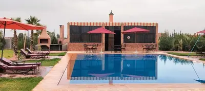 a pool with chairs and umbrellas next to a building at Igrane House in Marrakech
