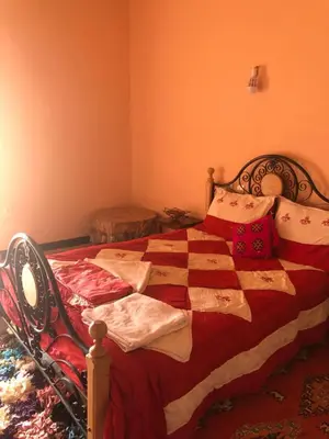 a bedroom with a bed with a red blanket and pillows at ACHAHOUD CHEz LA BELLE FIBULLE in Aït Fars