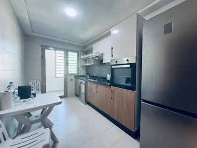 a kitchen with a stainless steel refrigerator and a table at Lo Belle Vie à Perstigia in Fès