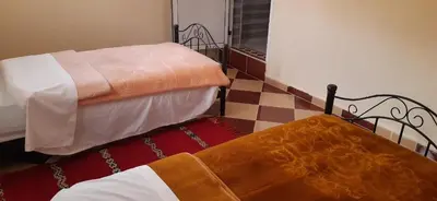 a bedroom with two beds and a checkerboard floor at Auberge l' avenir in Imilchil