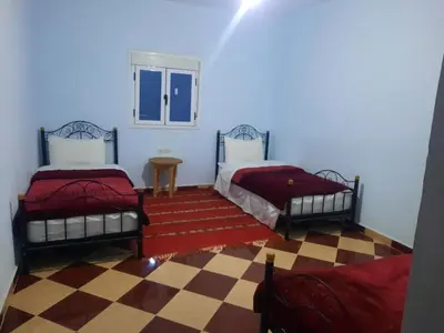 two beds in a room with a checkered floor at Auberge l' avenir in Imilchil