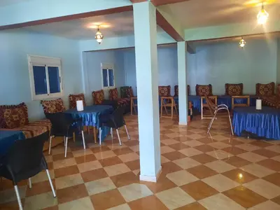 a dining room with blue tables and chairs in a room at Auberge l'avenir in Imilchil