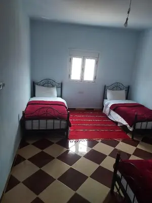 a room with two beds and a checkered floor at Auberge l'avenir in Imilchil
