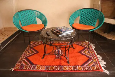 two chairs and a coffee table with a table and a rug at Maison D'hôtes IMINIGRAN & Spa in Ouarzazate