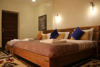 a bedroom with a large bed with blue pillows at Maison D'hôtes IMINIGRAN & Spa in Ouarzazate