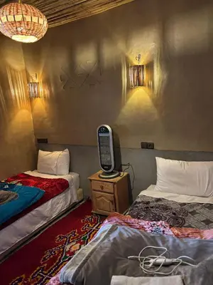 a room with two beds and a tv on a table at Auberge restaurant Afoud in Agoudal
