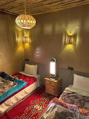 a room with two beds and a table with a lamp at Auberge restaurant Afoud in Agoudal