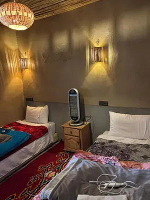 a room with two beds and a tv on a table at Auberge restaurant Afoud in Agoudal