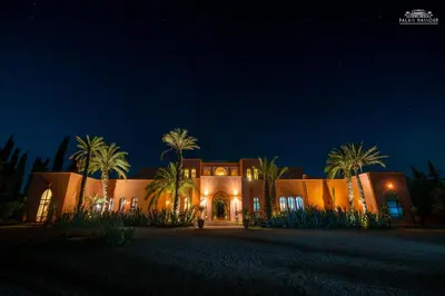 a home at night with palm trees in front at Palais Hassoun Marrakech in Oulad Snaguia