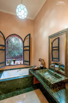 a bathroom with a large tub and a window at Palais Hassoun Marrakech in Oulad Snaguia