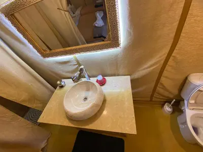 a bathroom with a sink and a mirror and a toilet at Merzouga Heart Luxury Camp in Merzouga