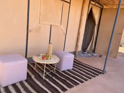 a table with a bowl of fruit on it in a tent at Merzouga Heart Luxury Camp in Merzouga