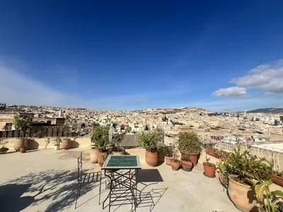 a table and chairs on a balcony with a view of a city at Riad Palais Bahia Fes in Fès