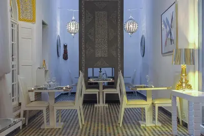 a dining room with two tables and chairs and blue walls at Riad Palais Bahia Fes in Fès