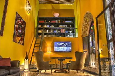 a living room with a table and chairs and a tv at Riad Palais Bahia Fes in Fès