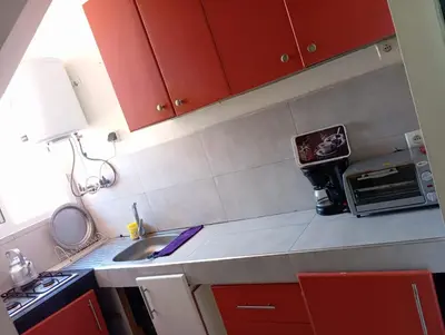 a small kitchen with red cabinets and a sink at maison Halima in Ifrane