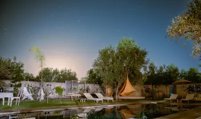 a backyard with a pool and chairs and a fence at Villa Roswell Marrakech in Marrakech