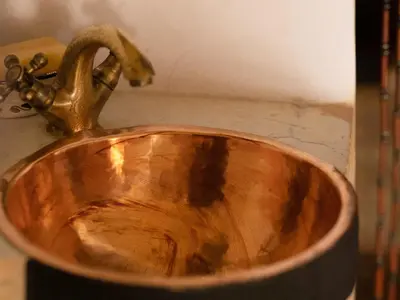 a wooden bathroom sink with a copper faucet at Riad 9 Fez in Fès
