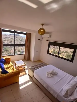 a bedroom with a bed and a couch and windows at La belle vue Elmazini in Demnat