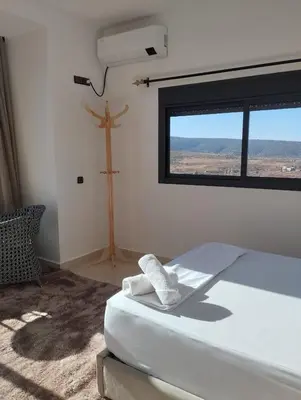 a bedroom with a bed and a window and a cross at La belle vue Elmazini in Demnat