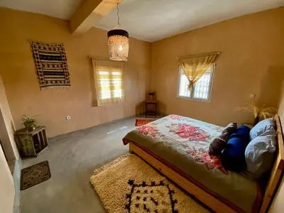 a bedroom with a bed and a rug and windows at Les chandelles in Tinerhir