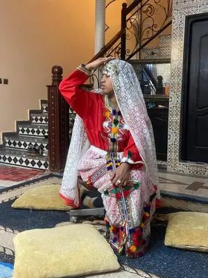 a woman is sitting on the floor in a dress at Riad Dar Fadma in Ouarzazate